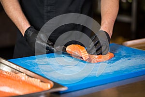Theme cooking is a profession of cooking. Close-up of a Caucasian man`s hand in a restaurant kitchen preparing red fish fillets