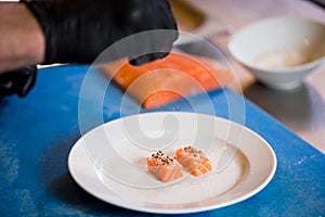 Theme cooking is a profession of cooking. Close-up of a Caucasian man`s hand in a restaurant kitchen preparing red fish fillets