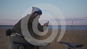 Theme is cycling in seaside. Male cyclist stopped to enjoy the sea view and see the road on the map on his smartphone. A