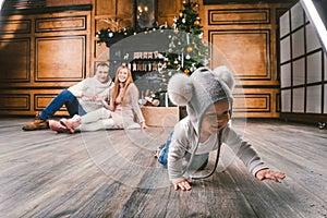 Family holiday New Year and Christmas. Young caucasian family mom dad son 1 year sit wooden floor near fireplace christmas tree on