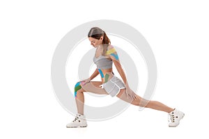 Theme kinesiology tape rehabilitation and health of athletes. girl doing exercise on white isolated background. On the