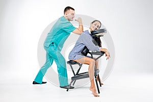 Theme massage and office. Male therapist with blue suit doing back and neck massage for young woman worker, business