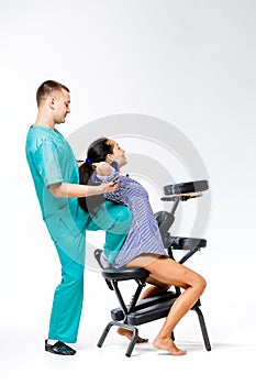 Theme massage and office. young male therapist in blue suit doing back massage with his knee braced in the spine of female worker,