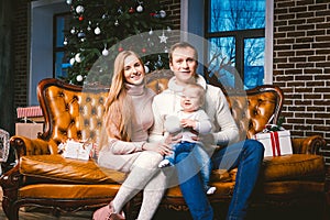 Theme new year and Christmas holidays in family atmosphere. Mood celebrate Caucasian young mom dad and son 1 year old sit on a