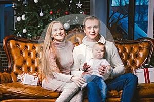 Theme new year and Christmas holidays in family atmosphere. Mood celebrate Caucasian young mom dad and son 1 year old sit on a