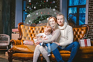 Theme new year and Christmas holidays in family atmosphere. Mood celebrate Caucasian young mom dad and son 1 year old sit on a