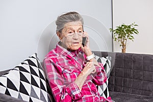 Theme old person uses technology. Mature happy joy smile active gray hair Caucasian wrinkles woman sitting home in