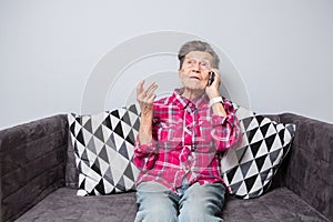 Theme old person uses technology. Mature happy joy smile active gray hair Caucasian wrinkles woman sitting home in