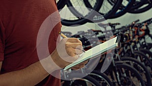 Theme of small business selling bicycles. Young Caucasian male brunette small business owner, store manager uses notepad