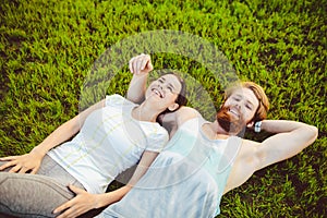 Theme is sport and a healthy lifestyle. A young man and woman couple are resting lying on their backs on the green grass, a lawn i
