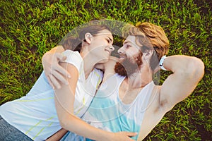 Theme is sport and a healthy lifestyle. A young man and woman couple are resting lying on their backs on the green grass, a lawn i