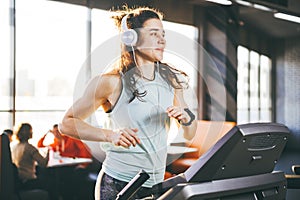 Theme is sport and music. A beautiful inflated woman runs in the gym on a treadmill. On her head are big white headphones, the gir