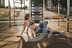 Theme sport and rehabilitation sports medicine. Beautiful strong slender Caucasian woman athlete uses foam roller green field stre