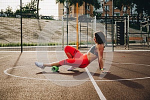 Theme sport and rehabilitation sports medicine. Beautiful strong slender Caucasian woman athlete uses foam roller green field stre