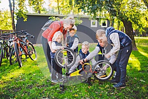 The theme is teamwork and a close-knit family spirit. Solving problems together. Big friendly family repairing a bike in the park