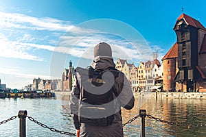 Theme of tourism in Poland. Traveling in Gdansk. A male traveler uses a phone on the embankment of the Motlawa River amid the main