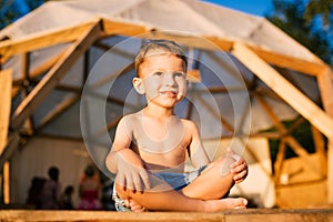 Theme is yoga and children. Caucasian Boy child sitting barefoot cross-legged in lotus position on wooden floor the