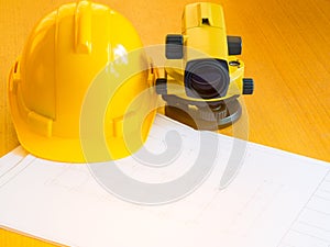 Theodolite and construction helmet, rolls and plans. on the desk.