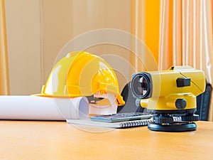 Theodolite and construction helmet, rolls and plans. on the desk. Construction industry concept.