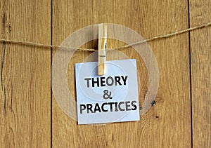 Theory and practice symbol. White paper with words `Theory and practice`, clip on wooden clothespin. Beautiful wooden background
