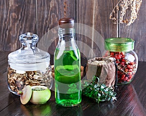 Therapeutic herbal tincture, alternative medicine, love potions, dried herbs on a wooden table.