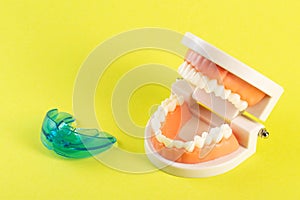 Therapeutic mouthguard on the background of a dental jaw mockup on a yellow background. Treatment of teeth grinding