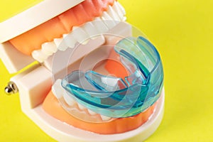 Therapeutic mouthguard on the background of a dental jaw mockup on a yellow background. Treatment of teeth grinding