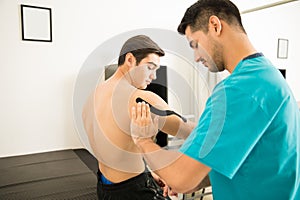 Therapist Applying Elastic Therapeutic Tape On Shoulder Of Shirt