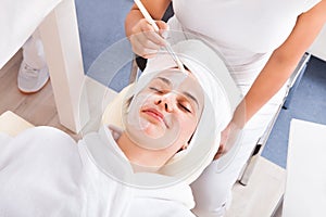 Therapist applying face mask to woman