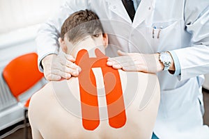 Therapist applying kinesio tape on a man`s neck