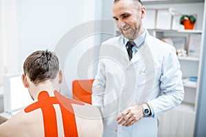 Therapist applying kinesio tape on a man`s neck
