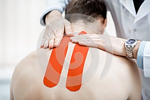 Therapist applying kinesio tape on a man`s neck