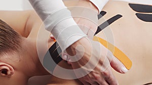Therapist is applying kinesio tape to female body. Physiotherapy, kinesiology and recovery treatment.