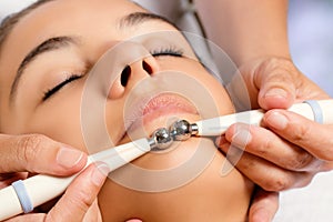Therapist applying low frequency galvanic electrodes on face.