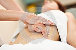 Therapist applying pressure on belly. Hands massaging woman abdomen.