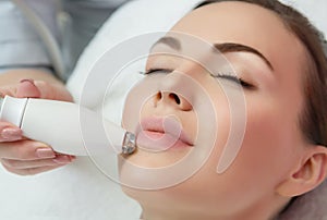 Therapist beautician makes a rejuvenating facial massage for the model by LPG apparatus  in a beauty salon