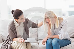 Therapist comforting upset woman on sofa