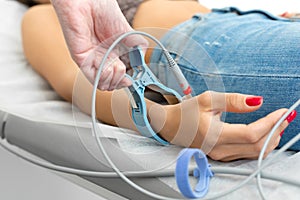 The therapist connects the electrocardiograph sensors to the patient`s hand