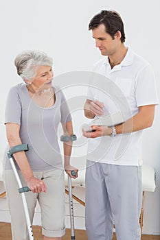 Therapist discussing reports with a disabled senior patient