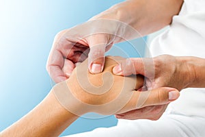 Therapist doing massage on female hand.