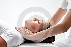 Therapist doing reiki on womanâ€™s neck.