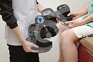 Therapist fitting a knee brace to patient knee in rehab