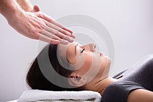 Therapist Giving Reiki Healing Treatment To Woman