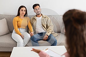 Therapist holding clipboard towards couple at office