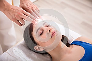 Therapist Performing Reiki Healing Treatment On Woman