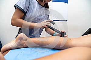 Physiotherapist using iastm tool performing leg therapy