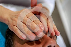 A therapist places his hands over the head of his patient