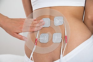 Therapist placing electrodes on woman's back