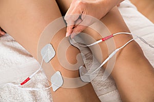 Therapist placing electrodes on woman's knee