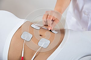 Therapist placing electrodes on woman's stomach